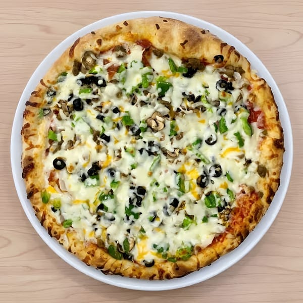 A whole pizza with melted cheese, green peppers, black olives, and mushrooms on a white plate.